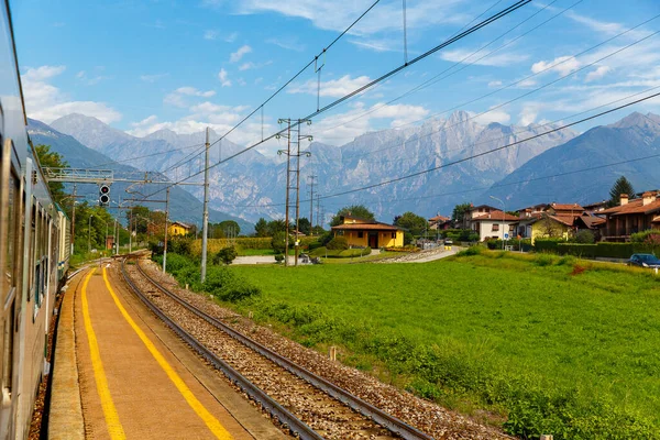 Alpler 'in arka planındaki bir İtalyan köyünün manzarasından geçen bir trenden görüntü.