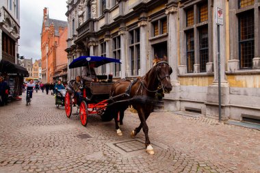 Bruges, Flanders, Belçika, Avrupa - 1 Ekim 2019. Brüj 'ün sonbaharında, ortaçağ sokaklarında at arabasında bilinmeyen insanlar ata biner.)
