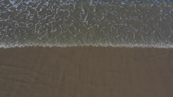Vagues de mer calme se brisant sur la plage de sable sous le ciel bleu