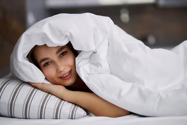 Tersenyum gadis berbaring di bawah selimut — Stok Foto