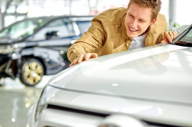 Mutlu genç adam tüm unsurları kontrol ediyor ve arabanın idealliğine bakıyor.