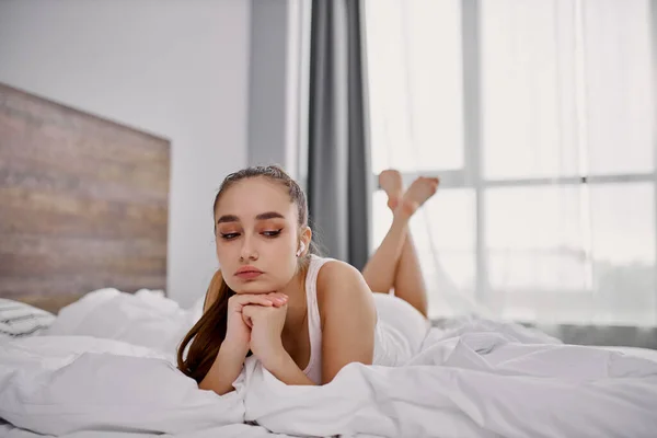 Traurige Frau hat melancholische Stimmung beim Musikhören im Bett — Stockfoto