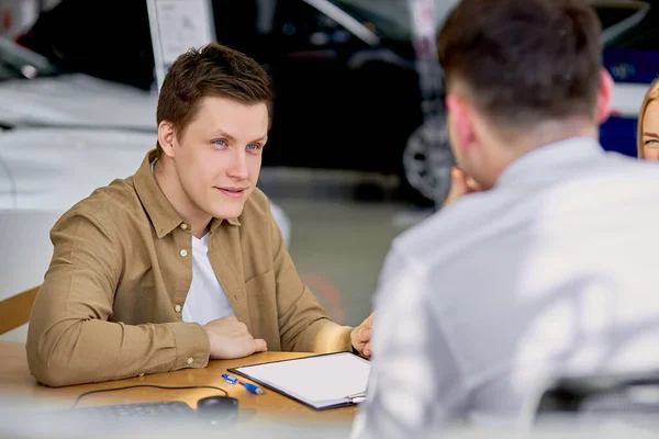 Serieuze klant luisteren naar verkoper alvorens document te ondertekenen — Stockfoto