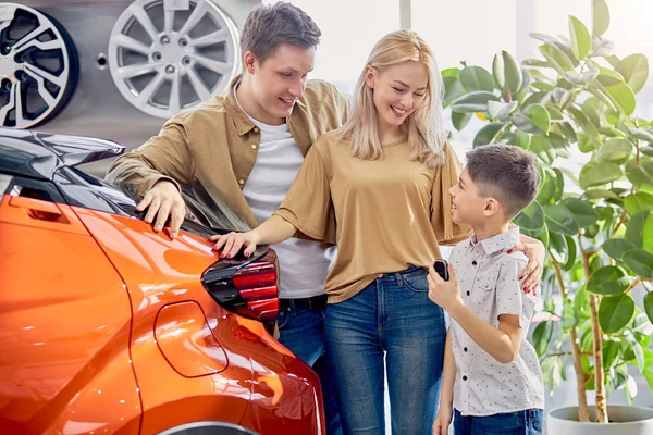 Adorável família caucasiana com criança em carros showroom — Fotografia de Stock