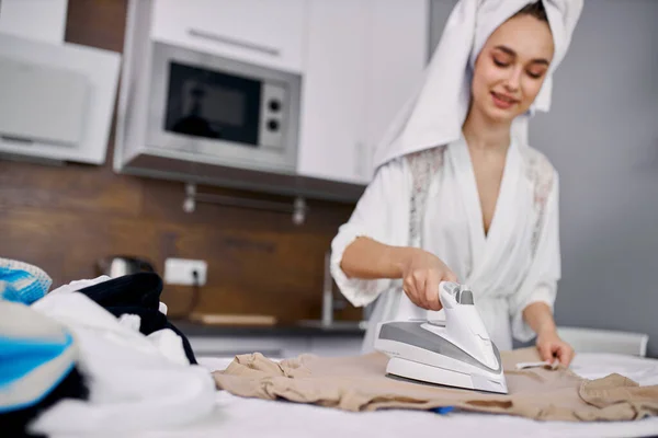 Ibu rumah tangga menggemaskan muda hati-hati menyetrika pakaian — Stok Foto