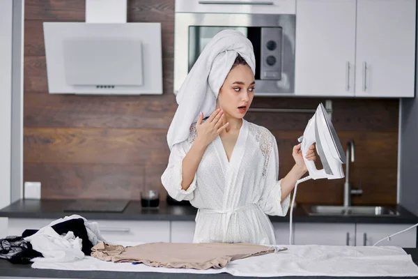 Schockierte Frau bügelt Kleidung zu Hause — Stockfoto