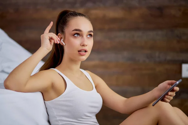 Charmig kvinna sjunger en melodi från hörlurar hemma — Stockfoto