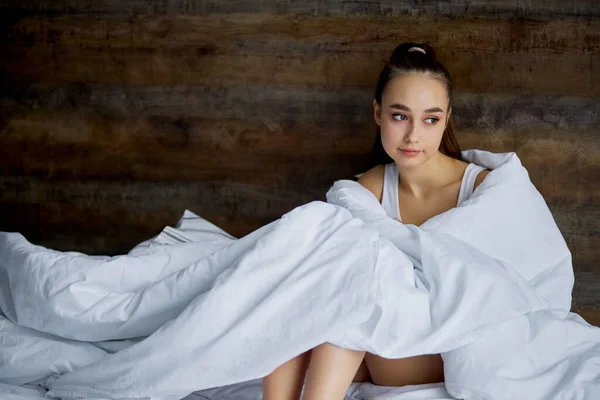 Allvarlig ledsen kvinna sitter på sängen efter att ha vaknat — Stockfoto