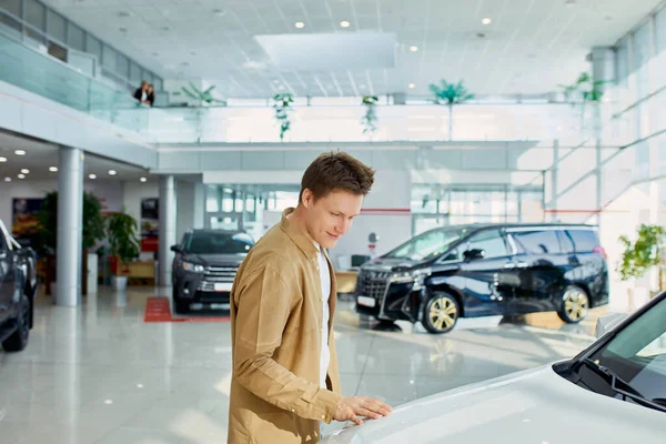 Cara bonito verificando, examinando carro novo antes de fazer a compra — Fotografia de Stock