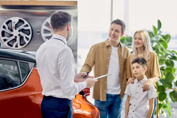 Família caucasiana feliz agora os proprietários de novo belo carro — Fotografia de Stock