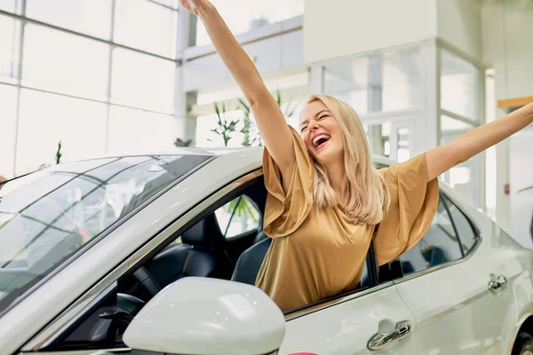 Jovem mulher grita com felicidade dentro do carro na concessionária — Fotografia de Stock