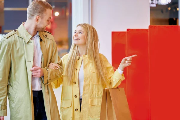 lets go there. woman show her husband on discounts in shop