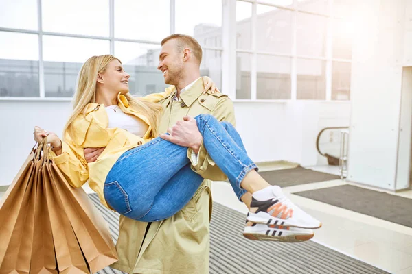 Man cirkelen in dans met een meisje zitten in zijn handen, na het winkelen — Stockfoto