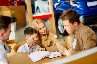 Müşteriler galerideki araba belgelerini dikkatle okuyorlar.