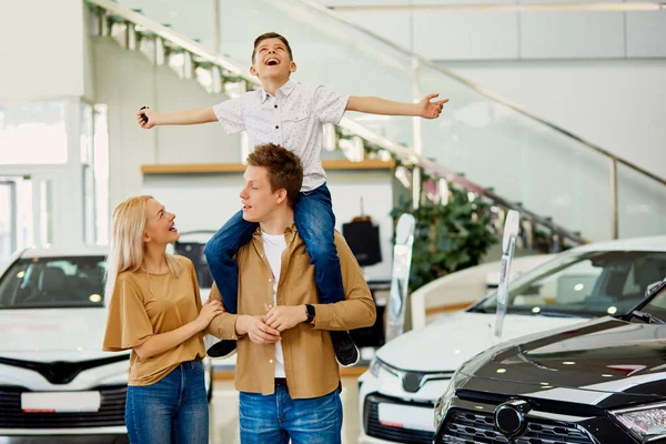 Família caucasiana feliz agora os proprietários de novo belo carro — Fotografia de Stock