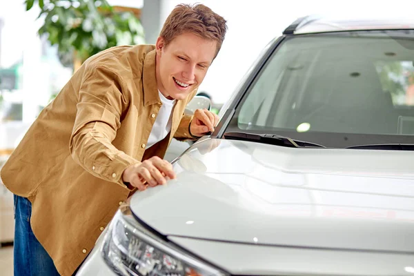 Cara bonito verificando, examinando carro novo antes de fazer a compra — Fotografia de Stock