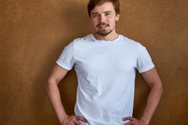 Säker lugn kille i t-shirt poserar vid kameran isolerad — Stockfoto