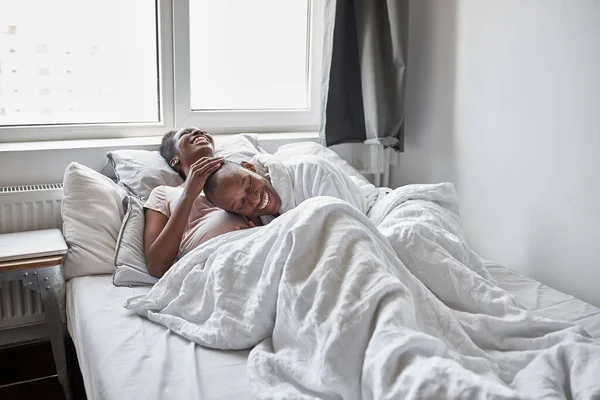 Schwarzer Mann kuschelt schwangere Frau auf dem Bett, berührt ihren Bauch — Stockfoto