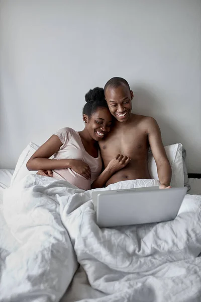 Guapo africano chico muestra algo en portátil a embarazada esposa — Foto de Stock