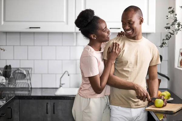 Ελκυστική κυρία αγκαλιάζει τον άντρα της ενώ ετοιμάζει φαγητό. — Φωτογραφία Αρχείου
