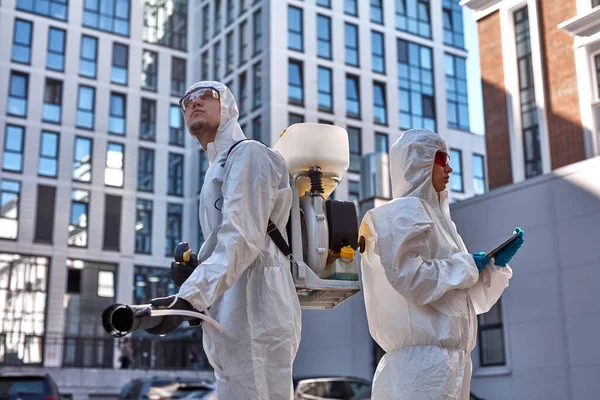 Especialistas en trajes de materiales peligrosos limpieza desinfectar las células del coronavirus epidemia, pandemia riesgo para la salud —  Fotos de Stock