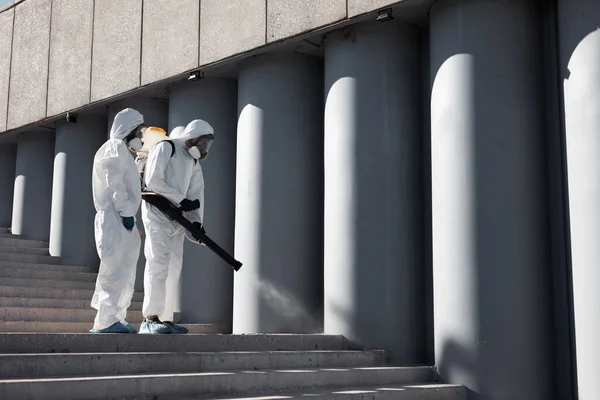 Απολύμανση της πόλης. επαγγελματίας εργαζόμενος σε προστατευτική στολή καθαρίζει τις σκάλες — Φωτογραφία Αρχείου