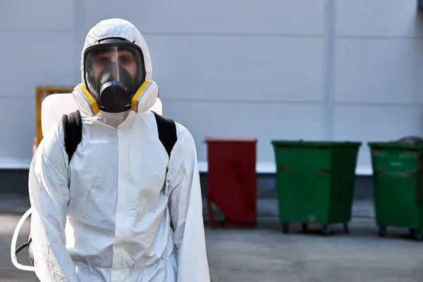 Hombre de traje blanco y protegido con desinfectante limpia las calles —  Fotos de Stock