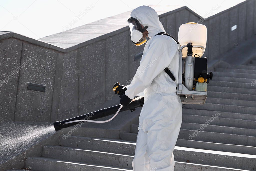 man in white full protected suit with disinfectant clean the streets