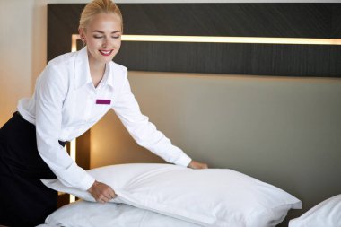 Otel odasında yatak yapan kadın oda hizmetçisi.