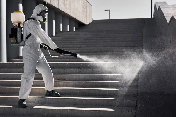 Young disinfector in hazard suit conducts disinfection in contaminated area — Stock Photo, Image