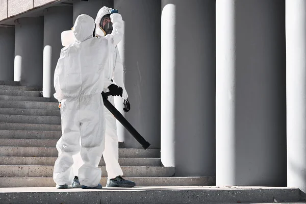 disinfection of the city. professional worker in protective suit cleans the stairs