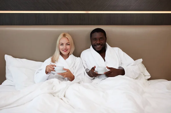 mixed race couple watch tv and have breakfast in hotel