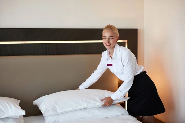 Beautiful housemaid changes the pillowcase on the bed — Stock Photo, Image