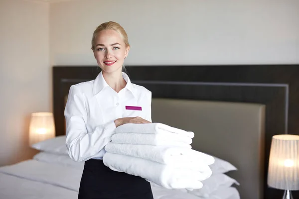 Mucama guapa con ropa blanca y toallas en las manos — Foto de Stock