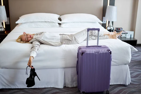 Mujer somnolienta tumbada en la cama en el hotel — Foto de Stock