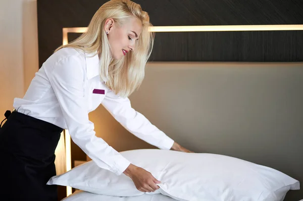 Chambermaid tidies the bed in hotel room — Stock Photo, Image