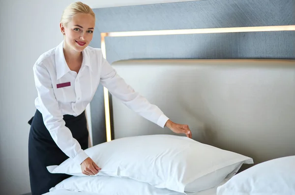 Beautiful housemaid changes the pillowcase on the bed — Stock Photo, Image