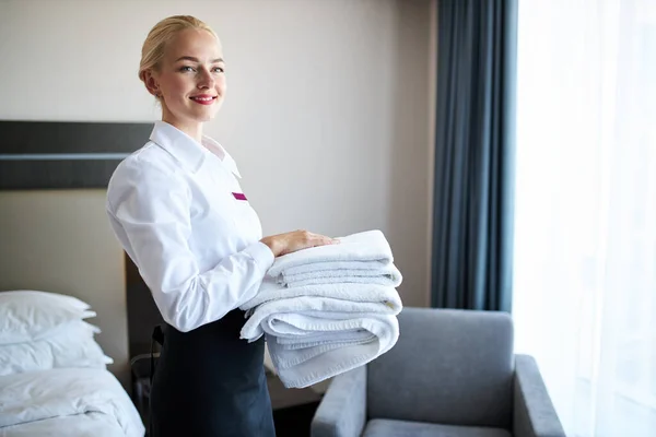 attractive chambermaid with towels in hands