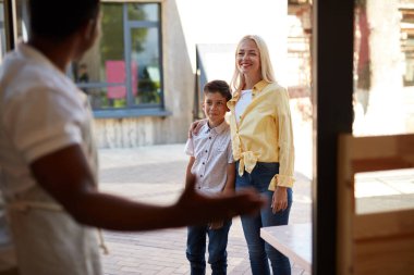 Yakışıklı, güler yüzlü adam müşterileri karşılar.