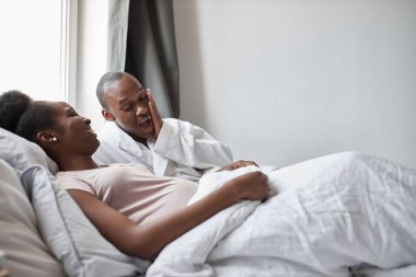 Şaşırmış Afrikalı genç adam güzel hamile karısına bakıyor.