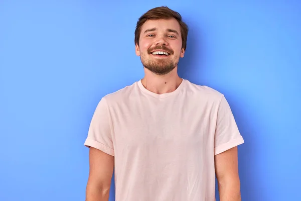 Zahmes Lächeln des positiven Mannes auf blauem Hintergrund — Stockfoto