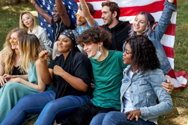 Amerikan melez ırkı gençliği çimenlerin üzerinde oturup eğleniyor.