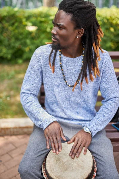 Dark-skinned musician plays on drums outdoors — Stock Photo, Image