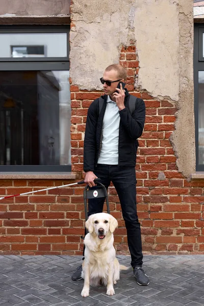 portrait of young blind man talking on phone, with dog