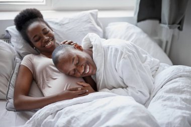 Mutlu Afrikalı adam hamile karısının karnını dinliyor.