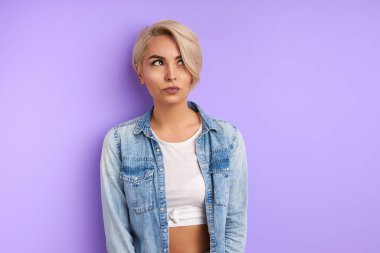 Esrarengiz genç kadın, mor arka planda izole edilmiş olduğunu düşünüyor.