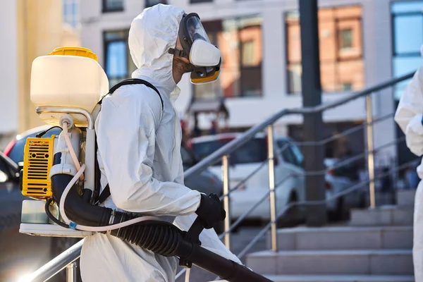 young sanitation worker in hazmat with pressure washer outdoors