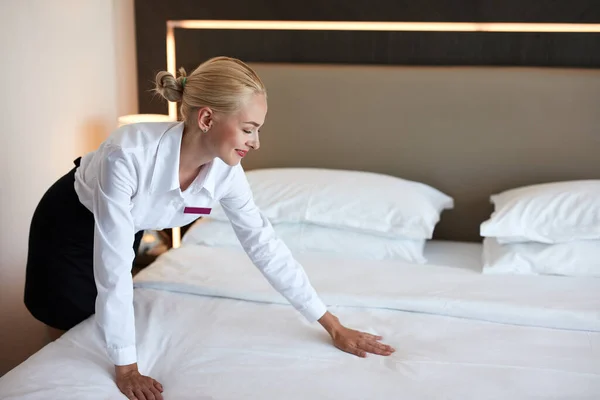 Nice maid prepares a bed for guests — Stock Photo, Image