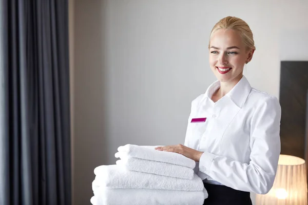 Good-looking chambermaid with white linen and towels in her hands — Stock Photo, Image