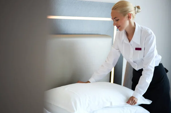 Chambermaid tidies the bed in hotel room — Stock Photo, Image